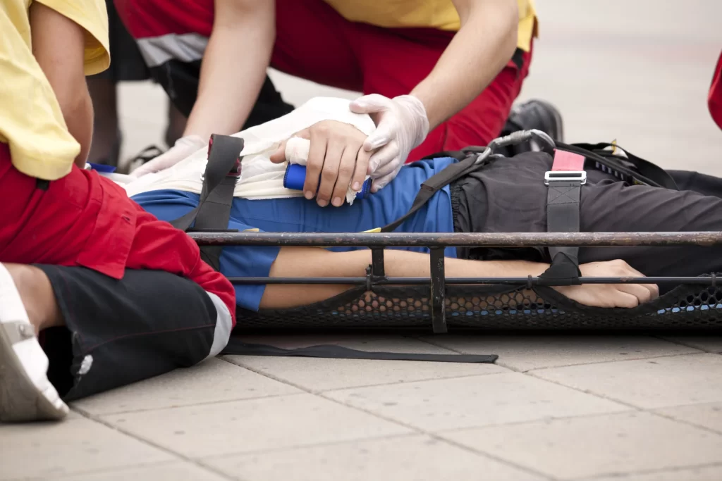 Person bent over injured on stretcher