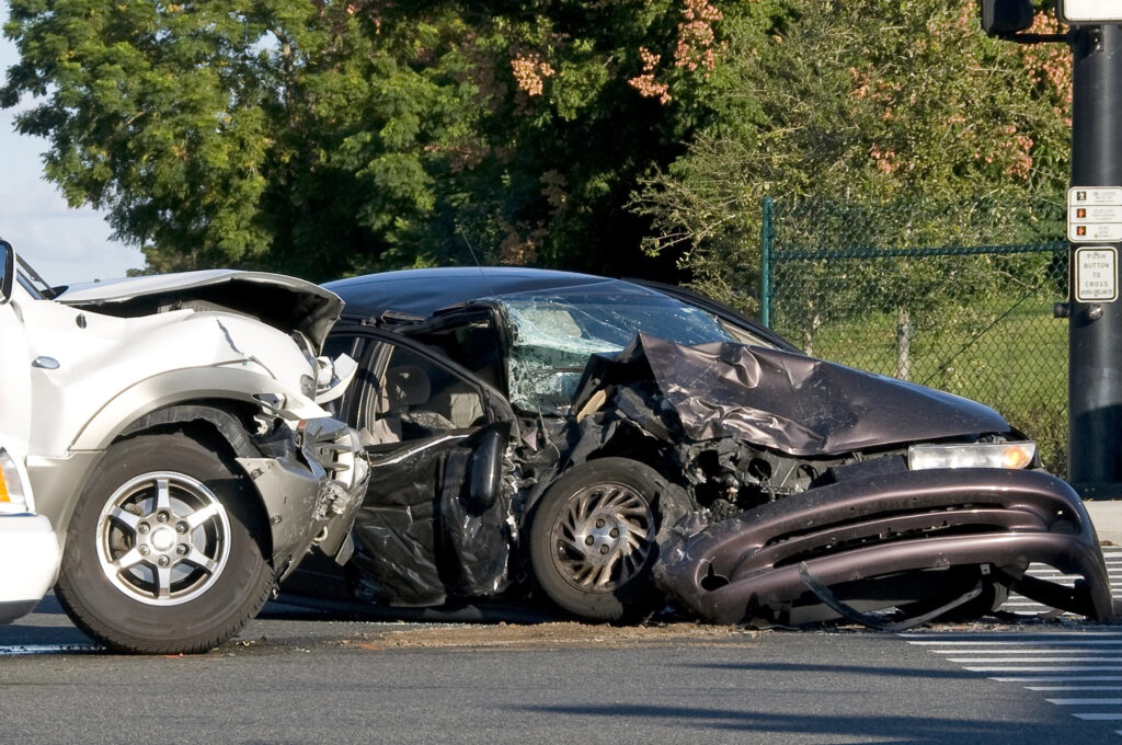 Two cars involved in a collision at an intersection, with significant damage to the front of both vehicles and debris visible on the road.