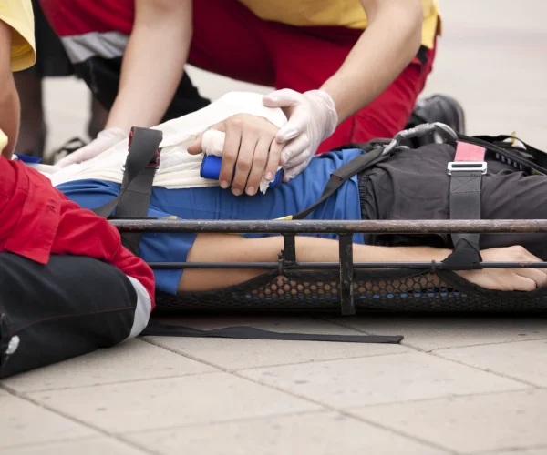 Person bent over injured on stretcher